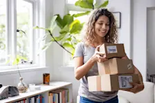 Foto: eine Frau trägt drei Pakete, mit worin Laptop und Handy verpackt wurden.