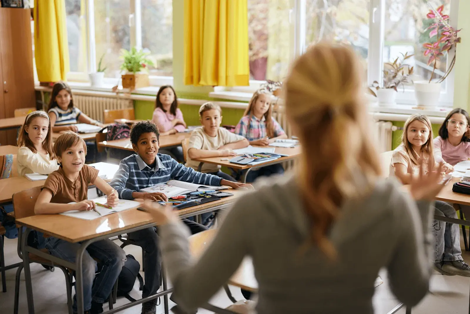 Foto: eine Lehrerin begrüßt ihre erste Klasse in der Grundschule.