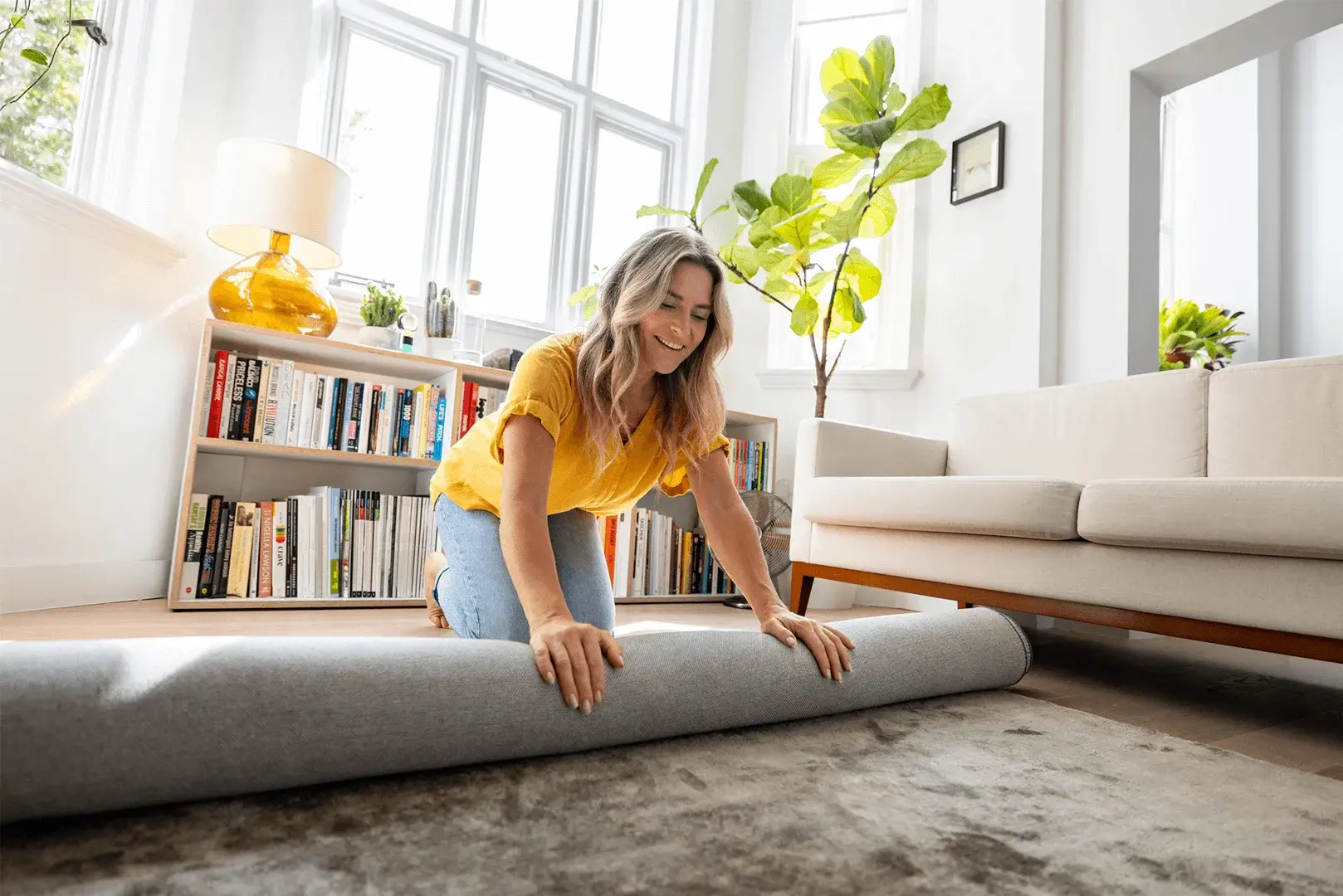 Foto: eine Frau rollt im Wohnzimmer einen Teppich zusammen