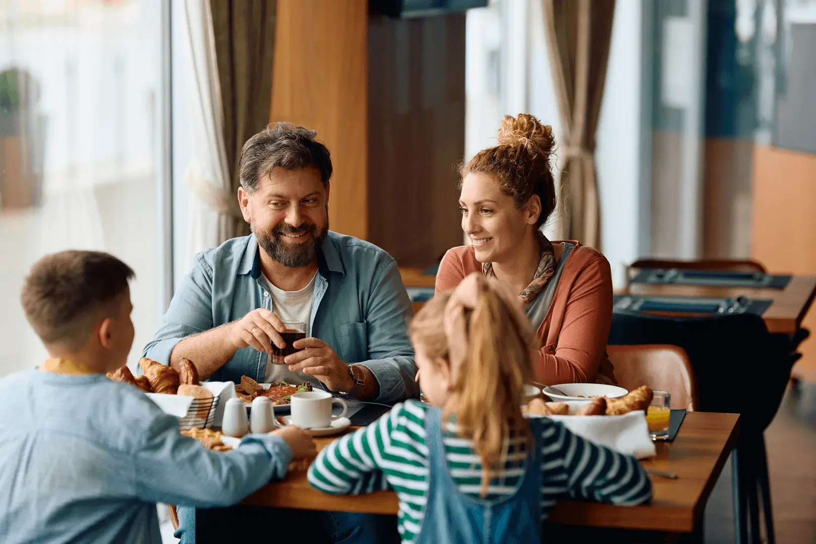 Foto: Familie frühstückt im Hotel und schmiert sich Brote