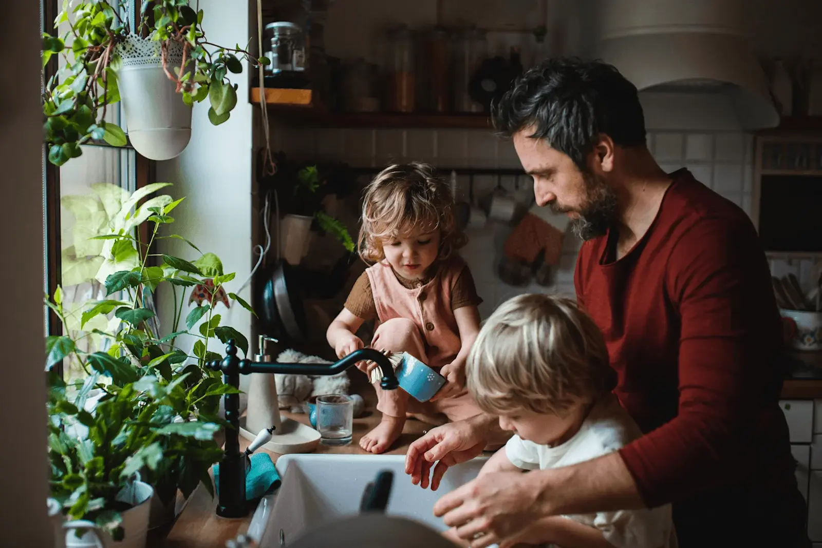 Foto: ein Vater spült mit seinen Kindern Geschirr ab