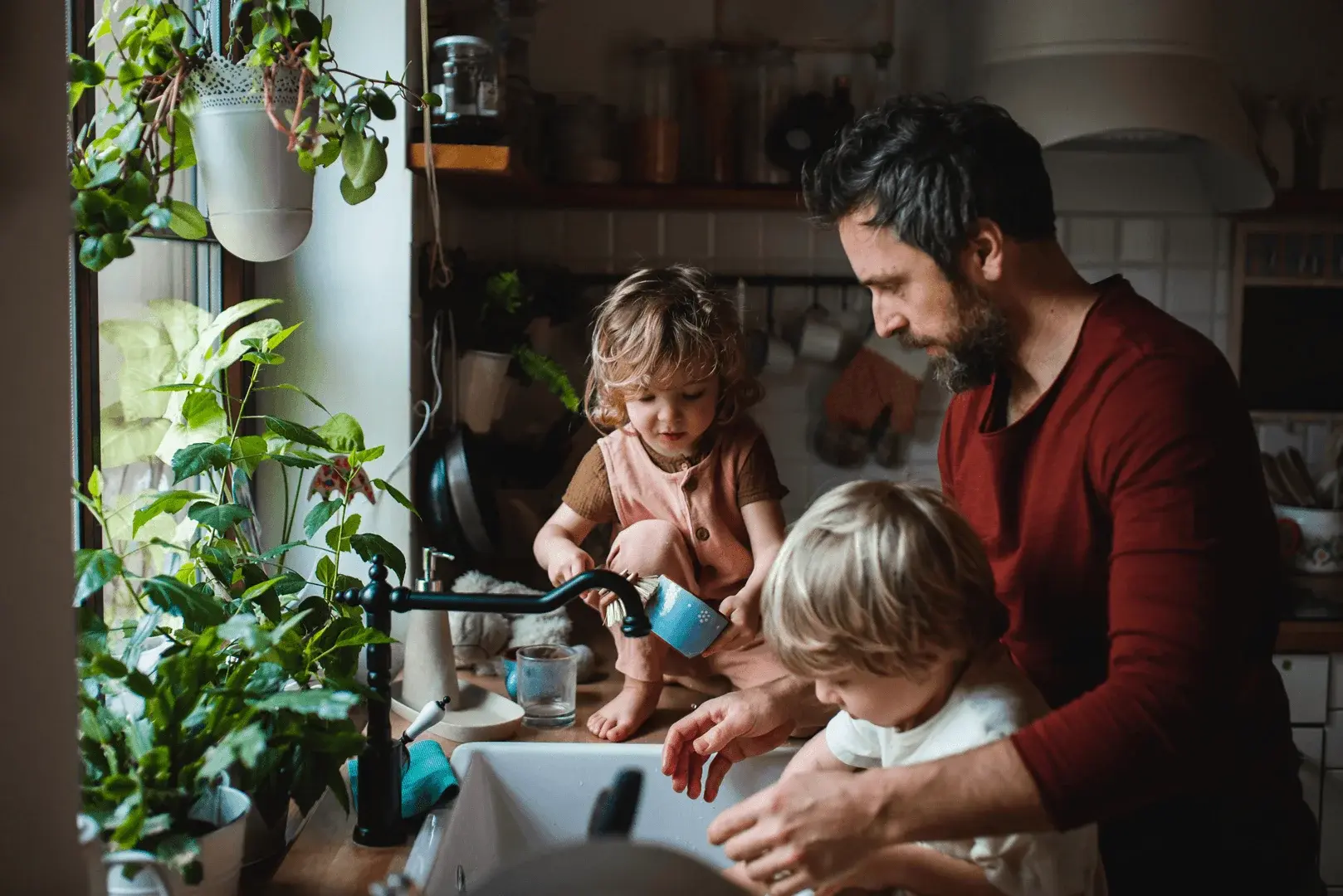 Foto: ein Vater spült mit seinen Kindern Geschirr ab