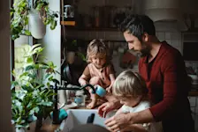 Foto: ein Vater spült mit seinen Kindern Geschirr ab