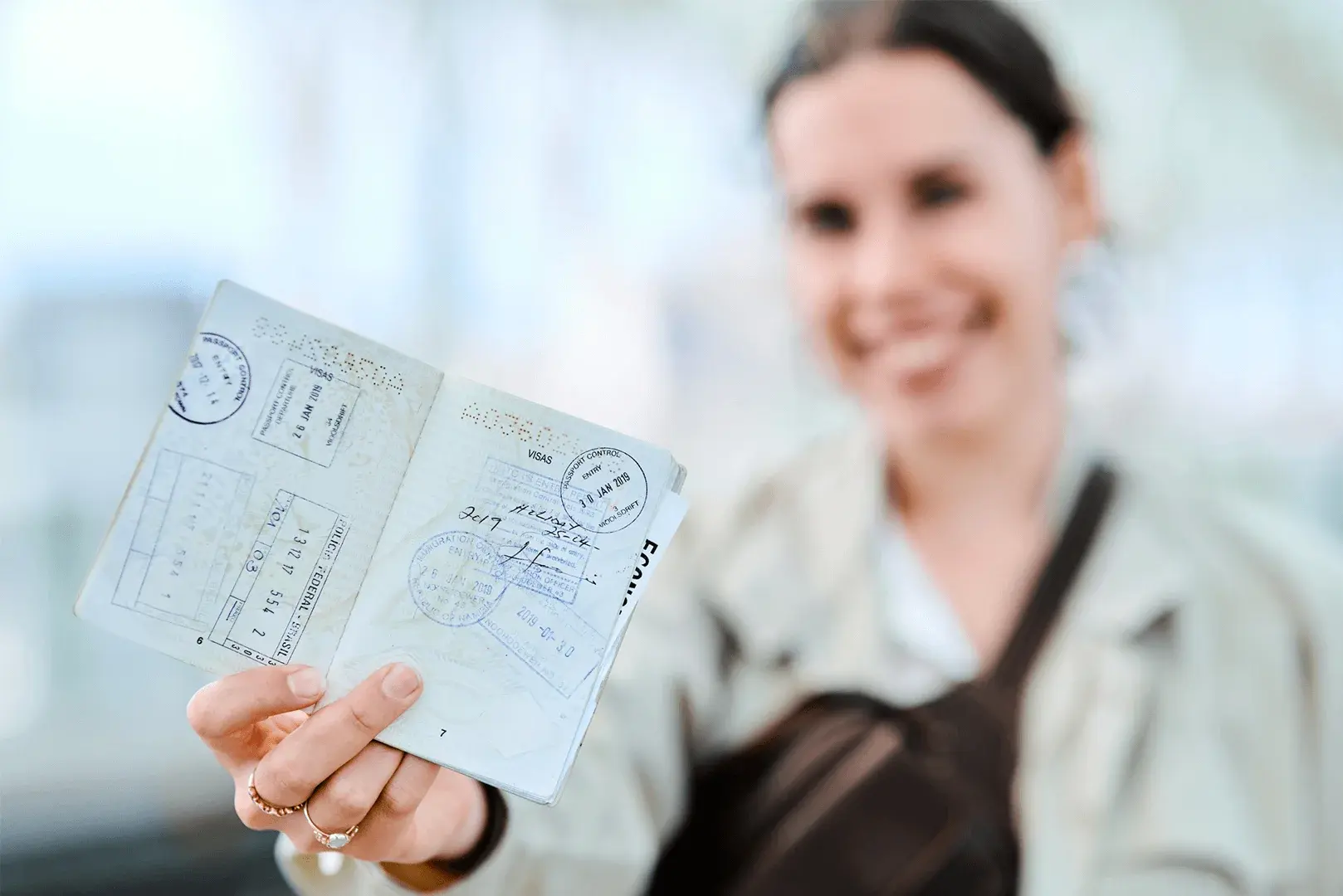 Foto: Eine Frau hält ihren Reisepass in die Kamera, der mit vielen Einreise Stempeln zeigt.