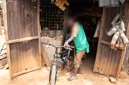 Rodrigue holds the bicycle he bought with his savings in front of his small shop at the IDP site in Alindao. ©OCHA/V. Bero, Basse-Kotto Prefecture, Central African Republic, 2022.