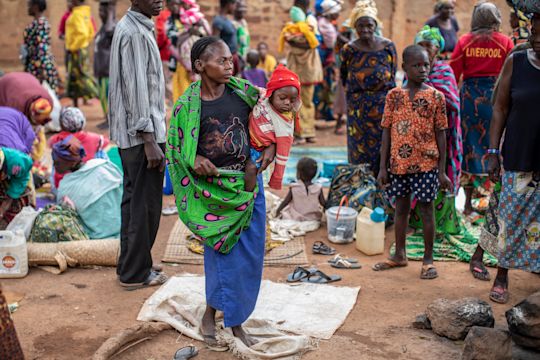 Mwala Georgette, 24, holds her baby boy, Kuri Isai, nine-months old by a church used to shelter families displaced due to the latest wave of unrest on March 17, 2021 in the capital Bangui. ©OCHA/Siegfried Modola, Bangui, CAR, 2021.