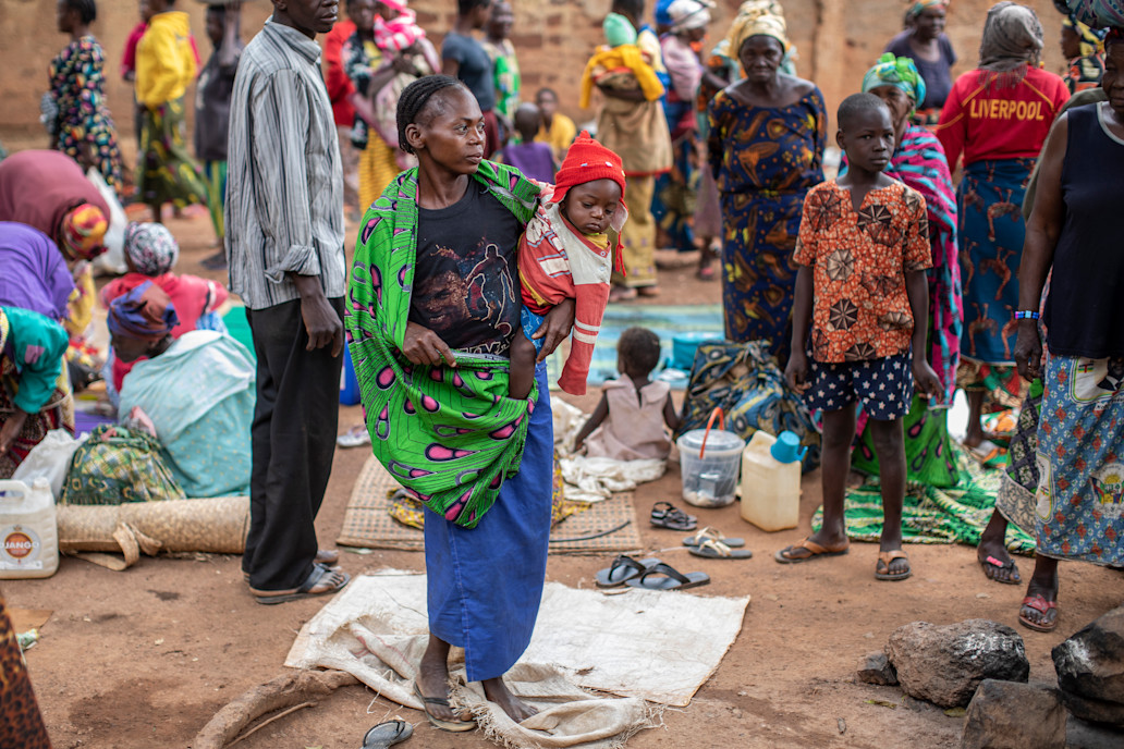 Mwala Georgette, 24 ans, tient son petit garçon, Kuri Isai, âgé de neuf mois, près d'une église utilisée pour abriter les familles déplacées en raison de la dernière vague de troubles dans la capitale Bangui.  ©OCHA/Siegfried Modola, Bangui, RCA, 2021.