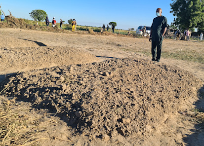 Resident and Humanitarian Coordinator standing before mass grave