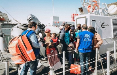 IOM personnel providing essential humanitarian services to recently rescued migrants and refugee families.