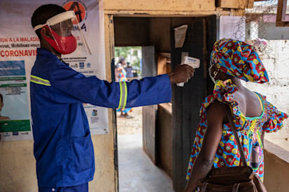 An employee measures the temperature of a patient, before she enters the Bimbo Hospital near the capital Bangui. The NGO ALIMA implements a project at the hospital to prevent COVID-19 and treat patients. ©OCHA/Siegfried Modola, Bangui, CAR, 2021.