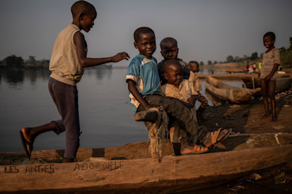 Des enfants déplacés jouent autour des pirogues traditionnelles en bois sur les rives du fleuve Oubangui, Bangui, RCA. ©OCHA / S. Modola