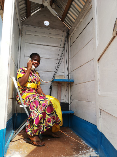 A displaced woman uses one of the new phone booths at the PK3 IDP site in Bria to stay in contact with her family. ©WFP/Elizabeth Millership, Bria, Haute-Kotto Prefecture, CAR, 2021. 