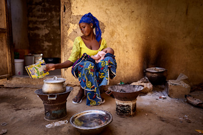 A displaced mother with her baby prepares some food