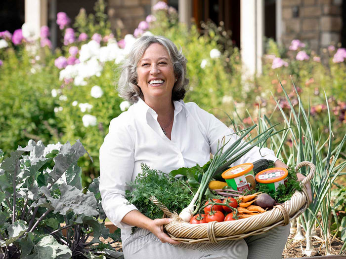 Una mujer sonriente cosecha verduras de un jardín