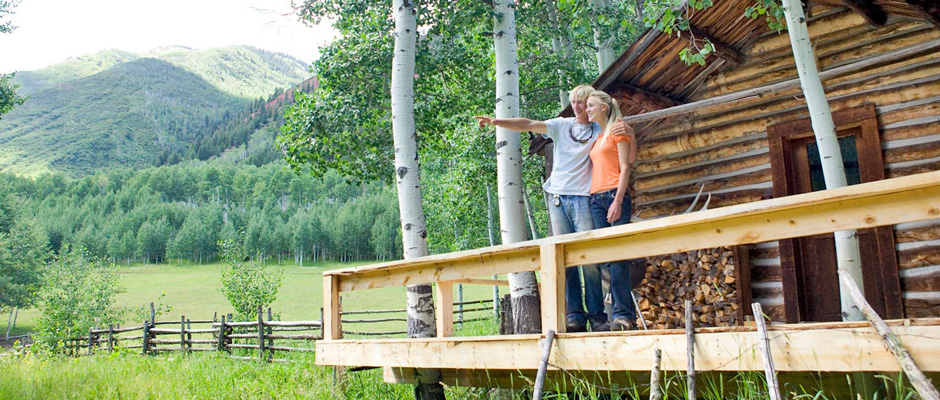 A couple on the deck of a mountain home