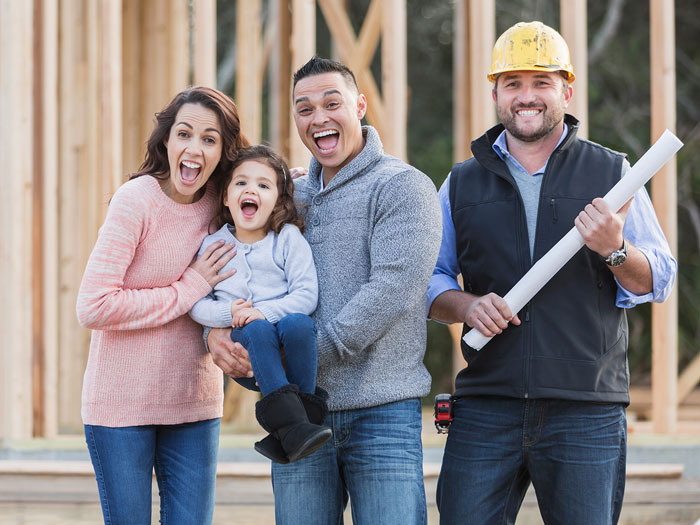 A couple stands in front of their new home with a builder.