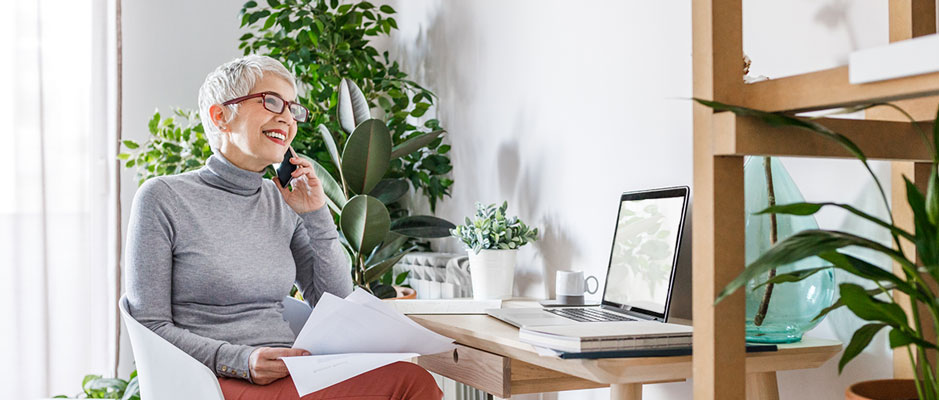 Woman on the phone with her broker in front of computer