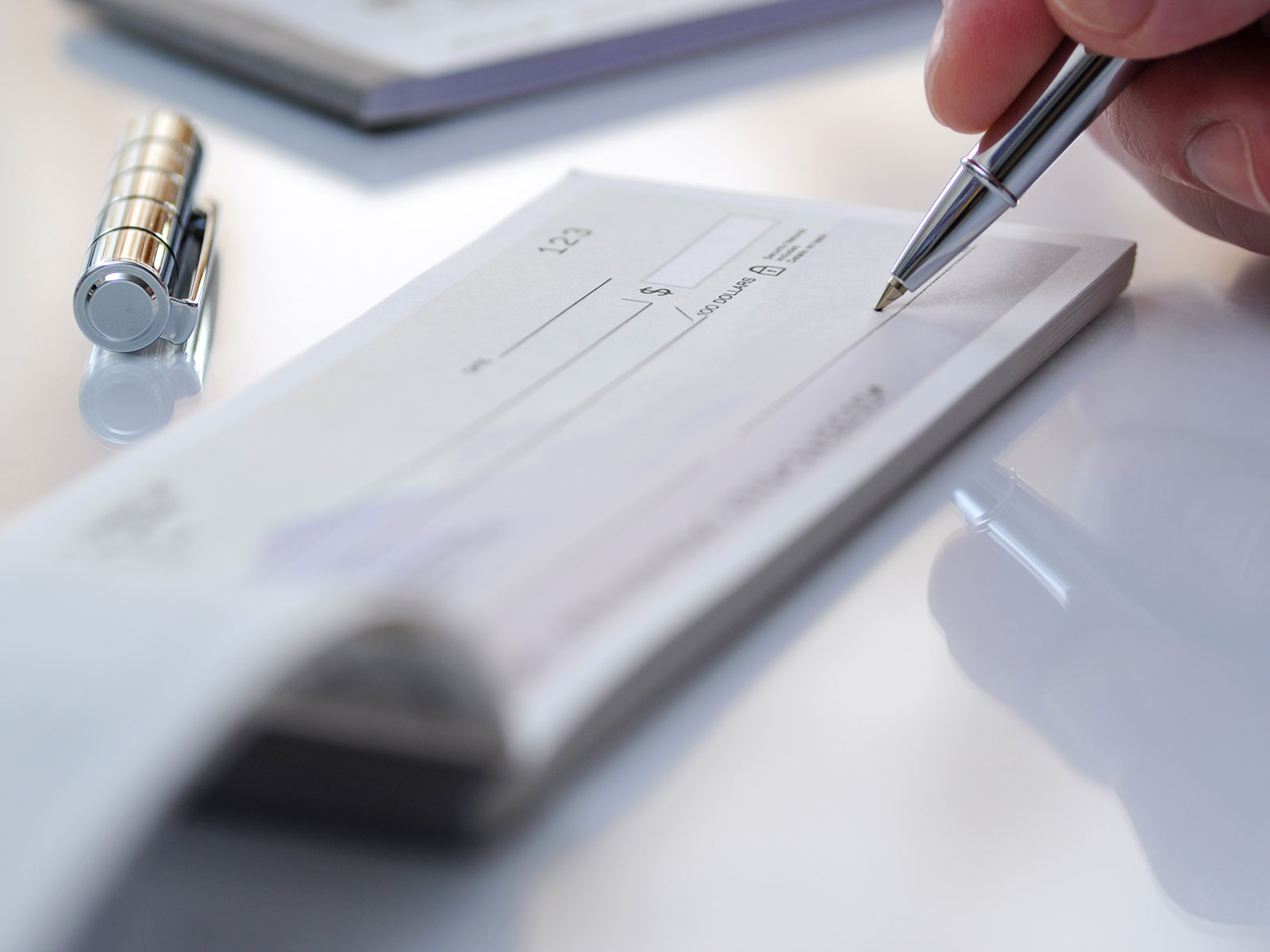 Close up of hand signing a check in a checkbook