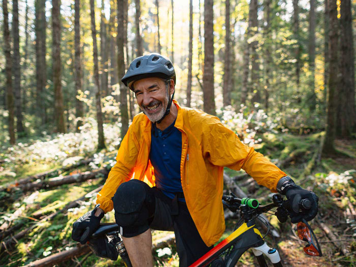 A man, on the woods, with a bike.