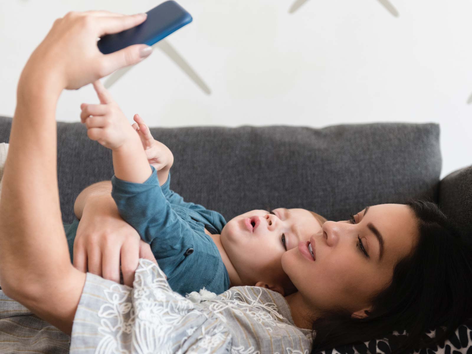 Madre e hijo acostados en un sillón y mirando el teléfono