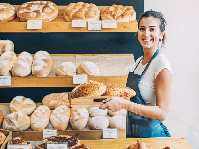 Mujer llenando los estantes con pan en una panadería