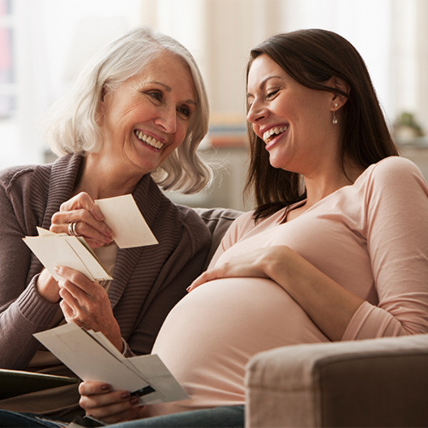 Mom and pregnant daughter looking at old picture