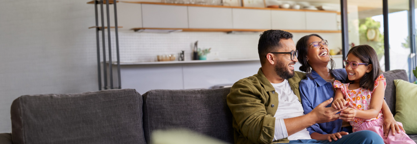 Family of 3 on the couch smiling