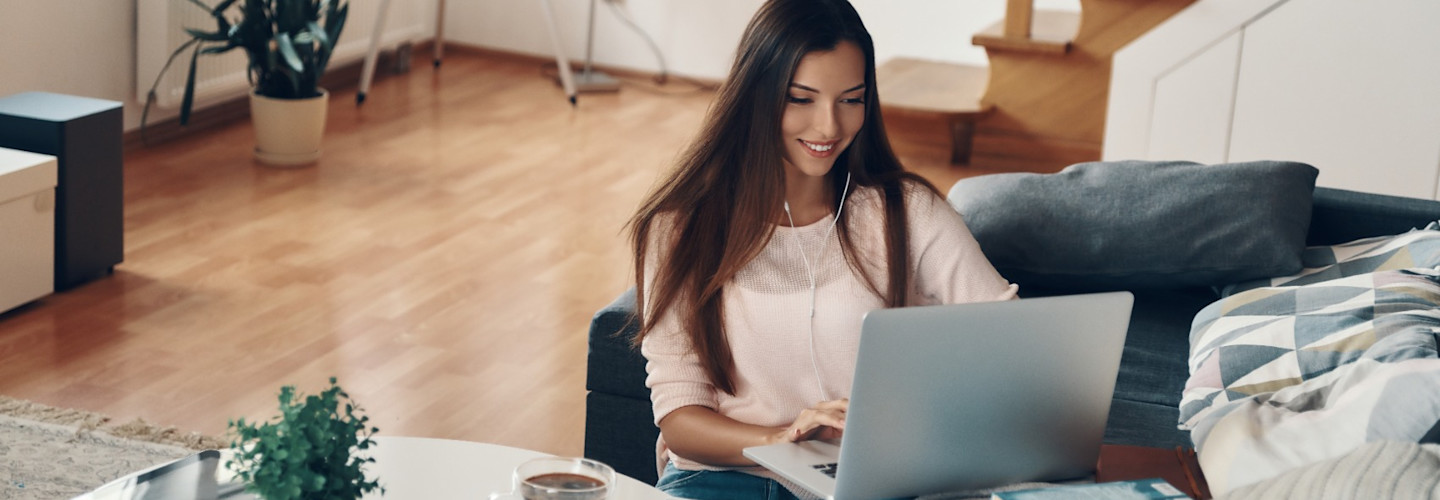 Beautiful young woman in casual clothing using laptop while resting at home