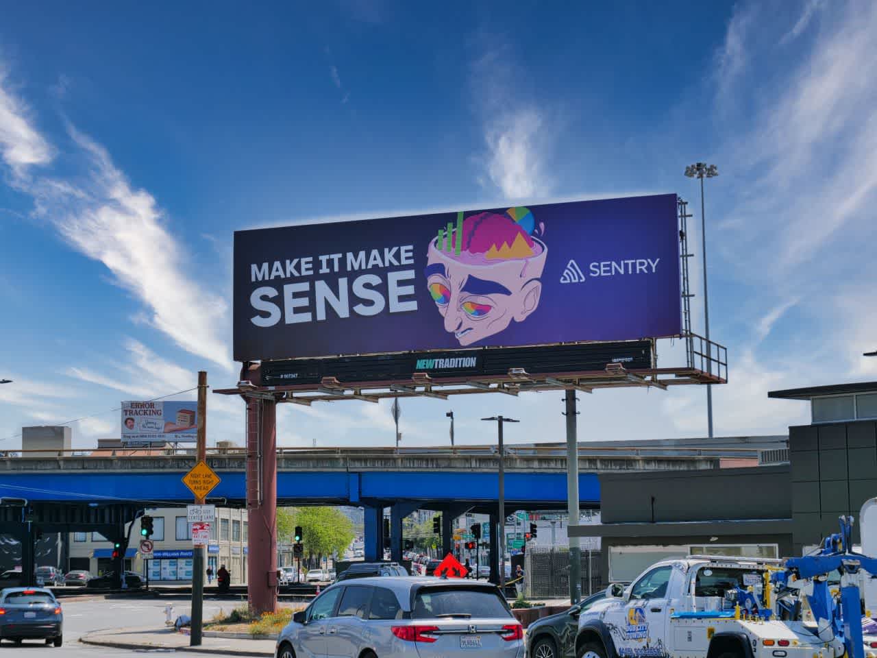 A large billboard on the corner of a busy San Francisco intersection, advertising Sentry with the slogan “Make it make sense”.