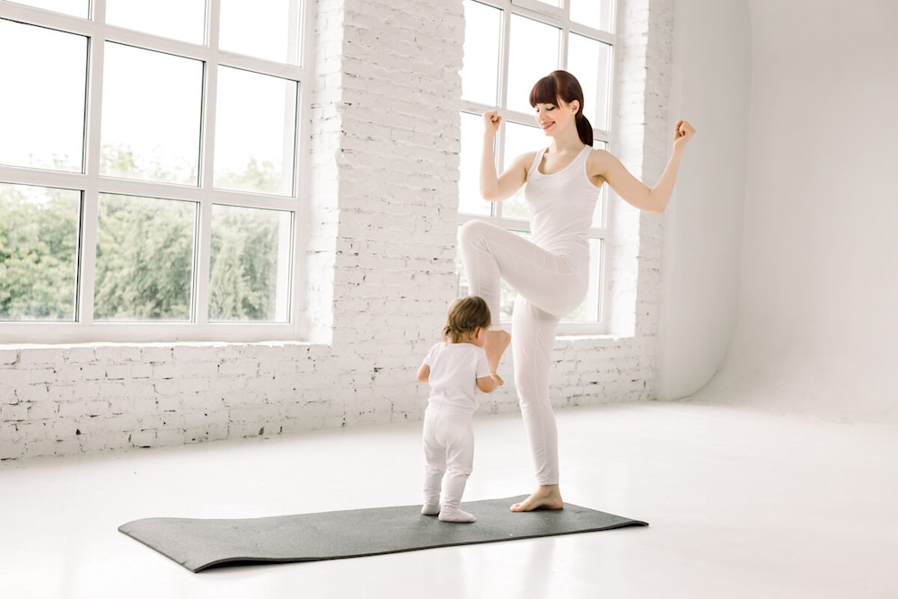 Mother doing some standing bicycle crunches with her baby
