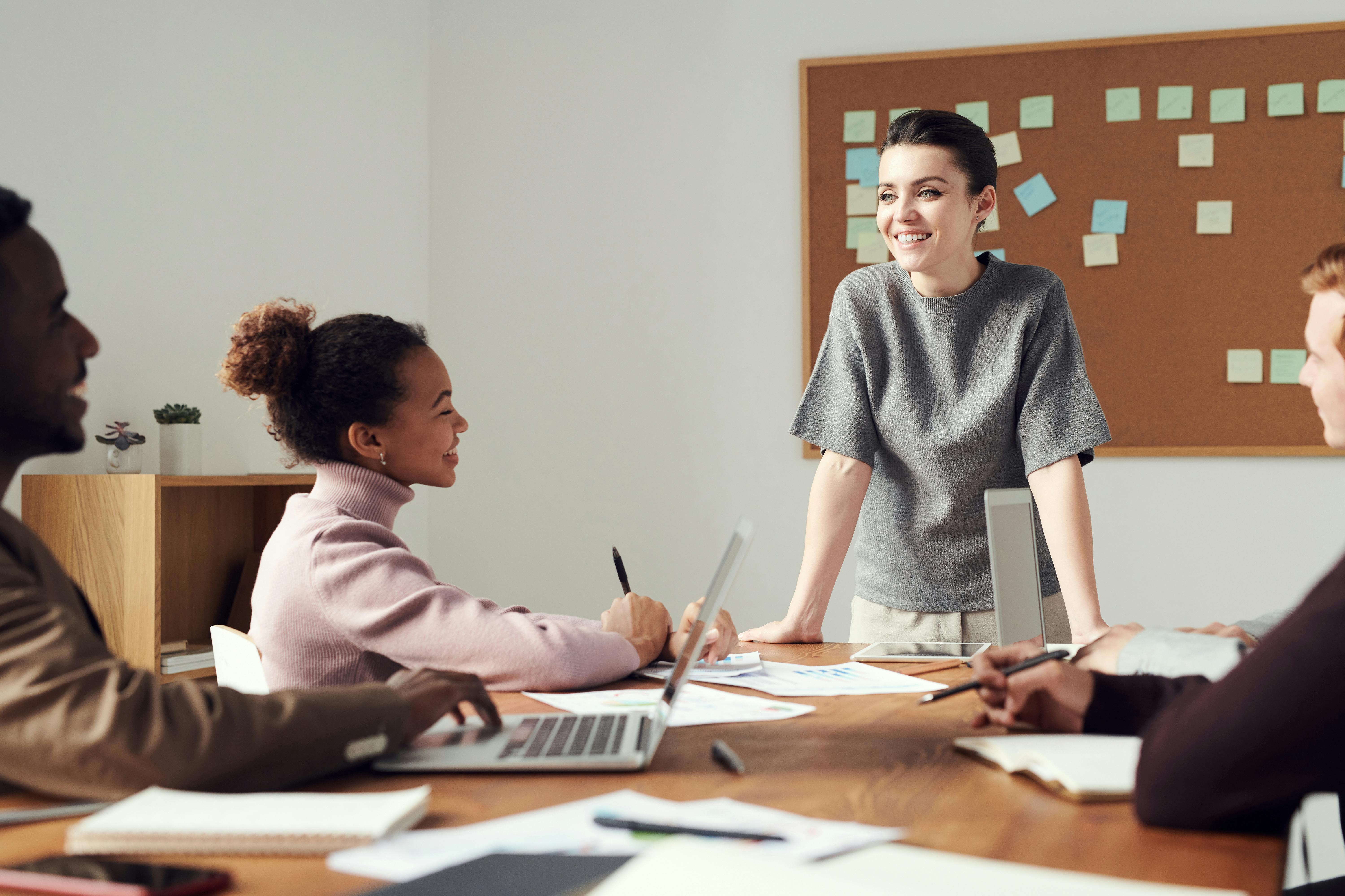 A group of people holding a meeting with a woman leading