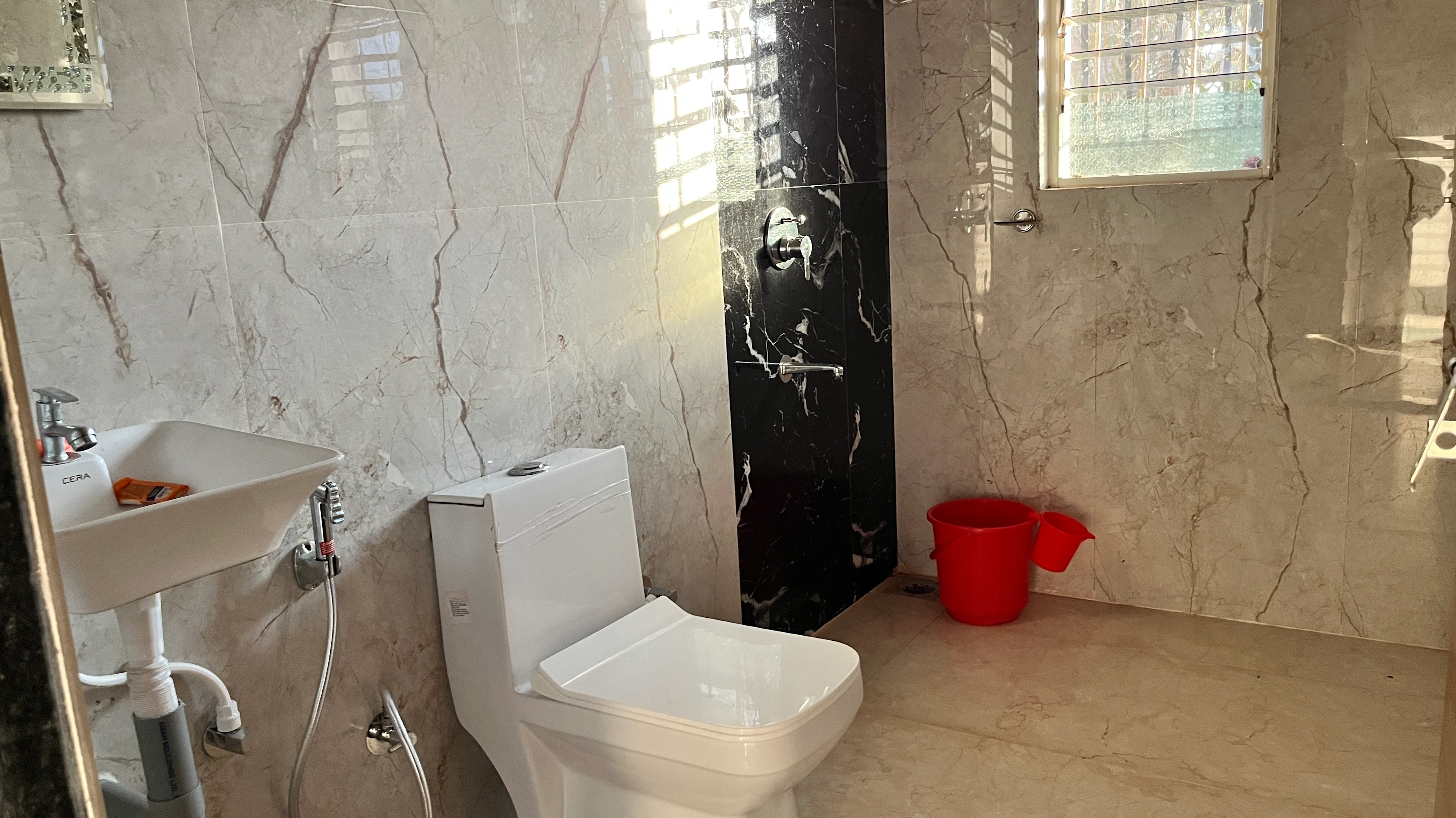 Ensuite bathroom with warm laterite tones at Blossom Retreat, Chiplun farmstay