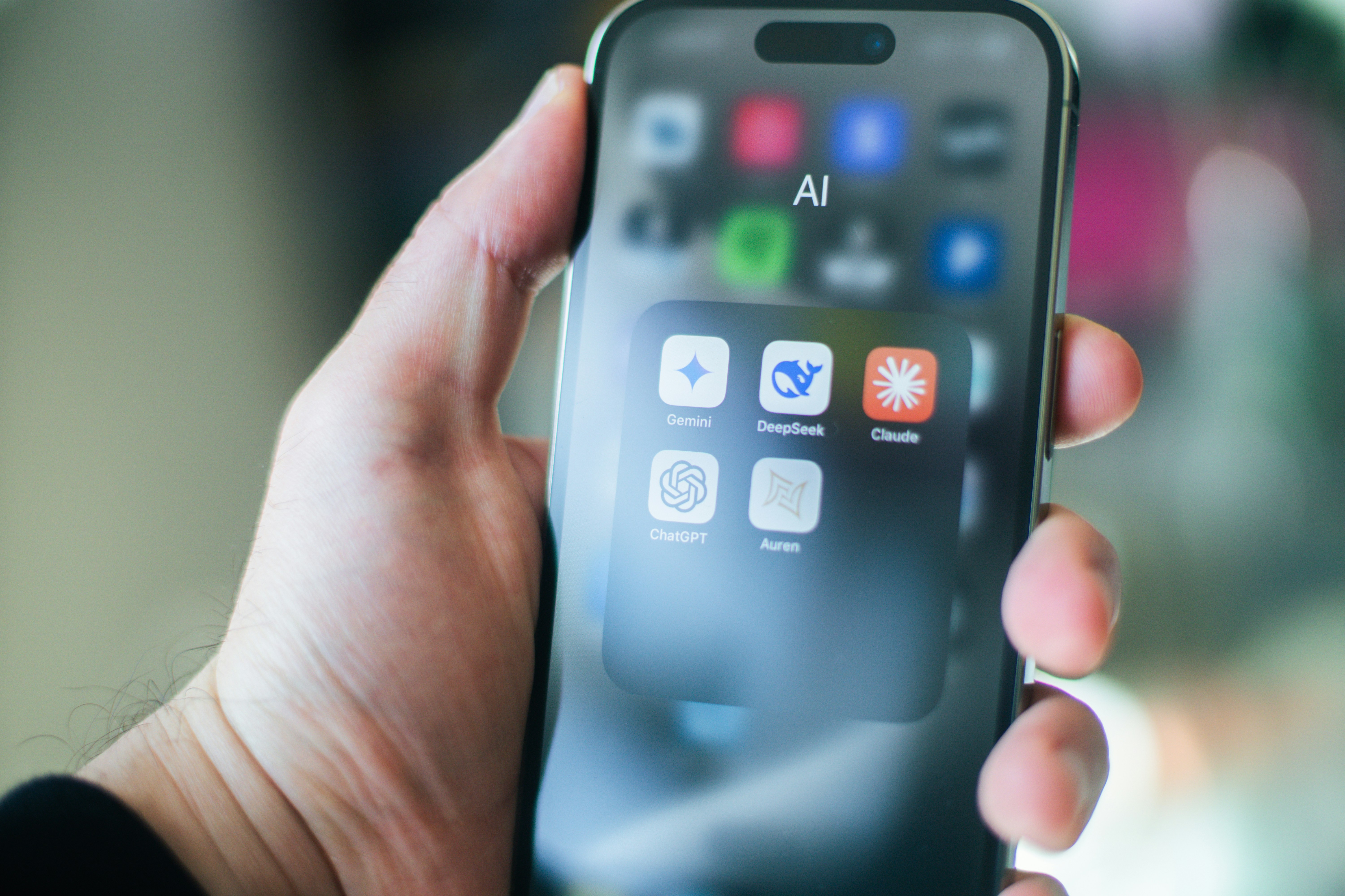 Person holding smartphone displaying AI tools like ChatGPT, Gemini, DeepSeek, and Claude—representing the evolution of AI SEO and search innovation.