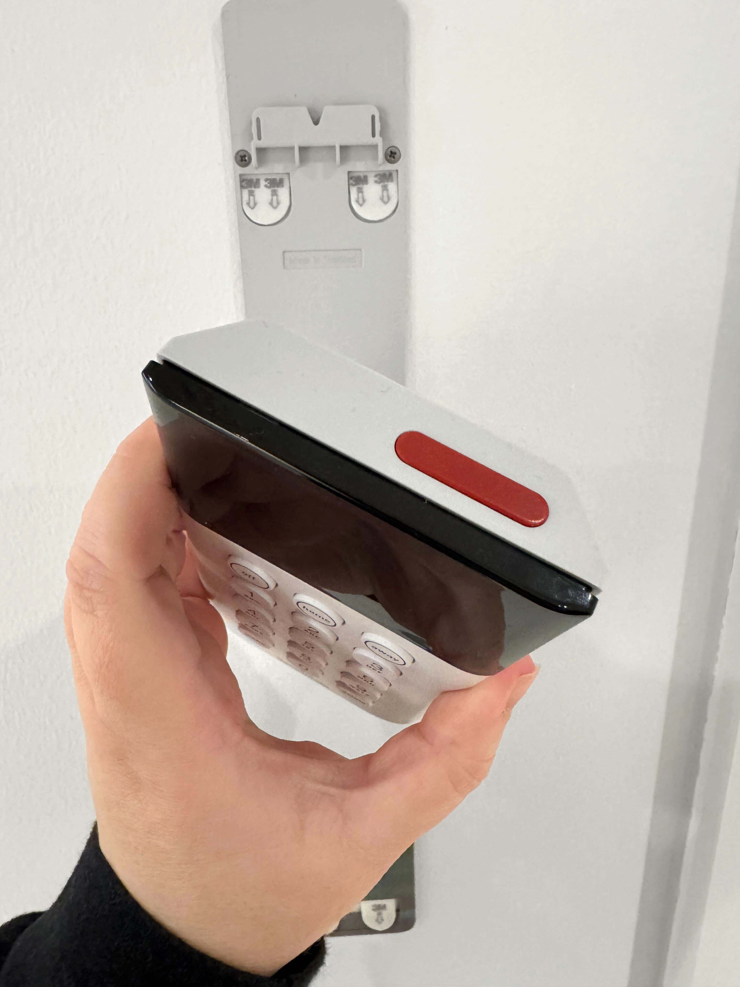 The Keypad being held at an angle where the red button on the top of it is visible, highlighting the built-in Panic Button feature