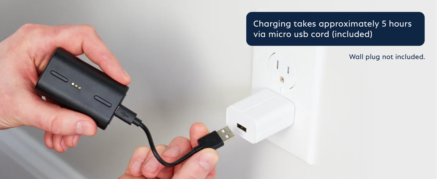 A person holding the Outdoor Camera battery with a charging cable, plugging it into a USB power brick.