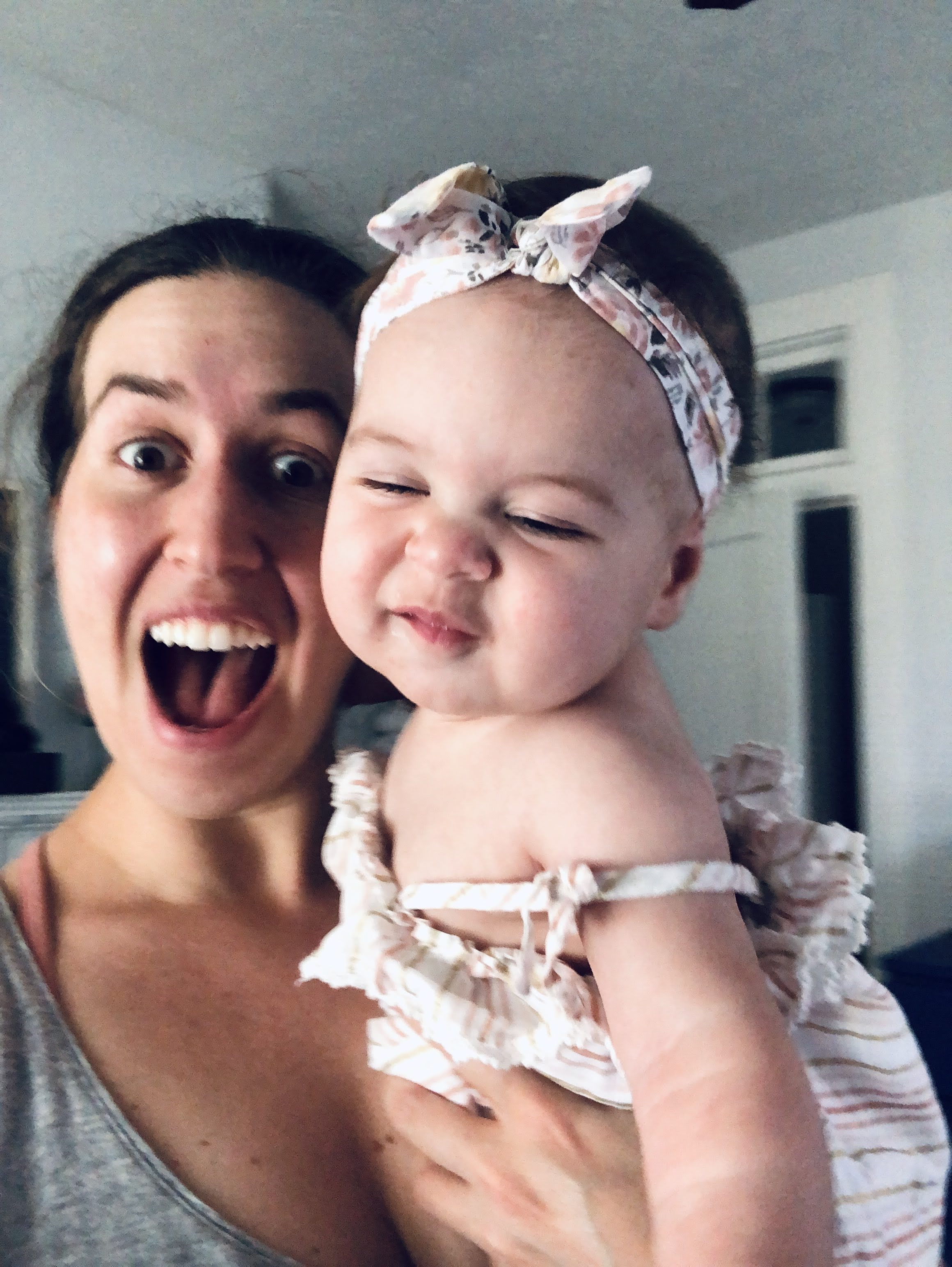 Woman holding a baby girl wearing a pink bow that matches her pink outfit