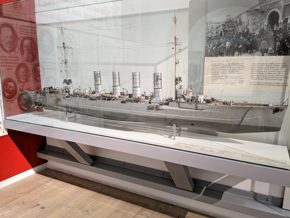 Display case with a large grey model of the cruiser Breslau, and a photograph of a crowd in Istanbul behind it