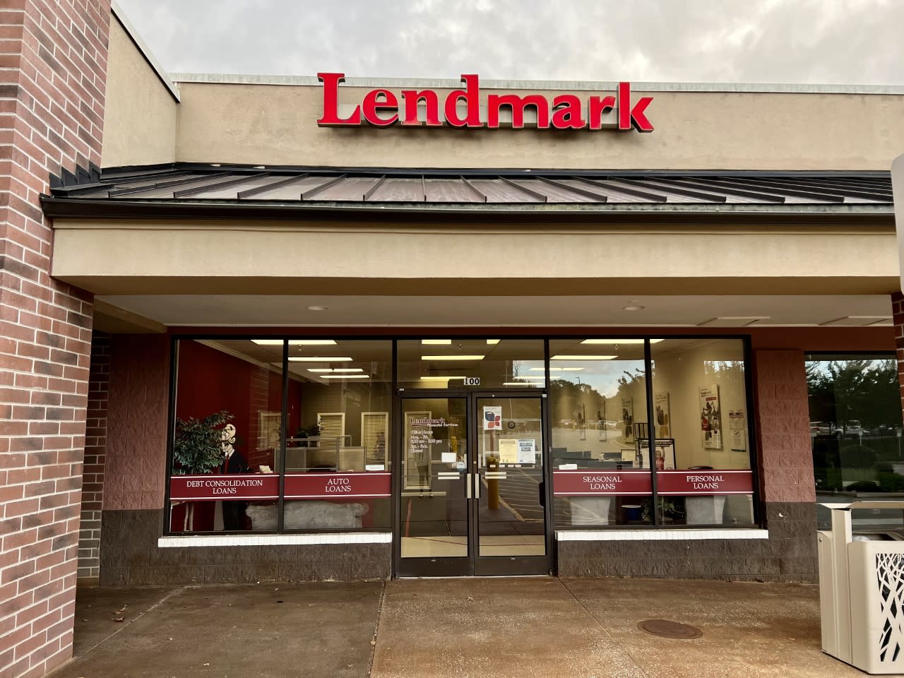 A storefront with large windows and a red "Lendmark" sign above. Loan types like "Auto" and "Personal" are displayed. The setting is clean and inviting.