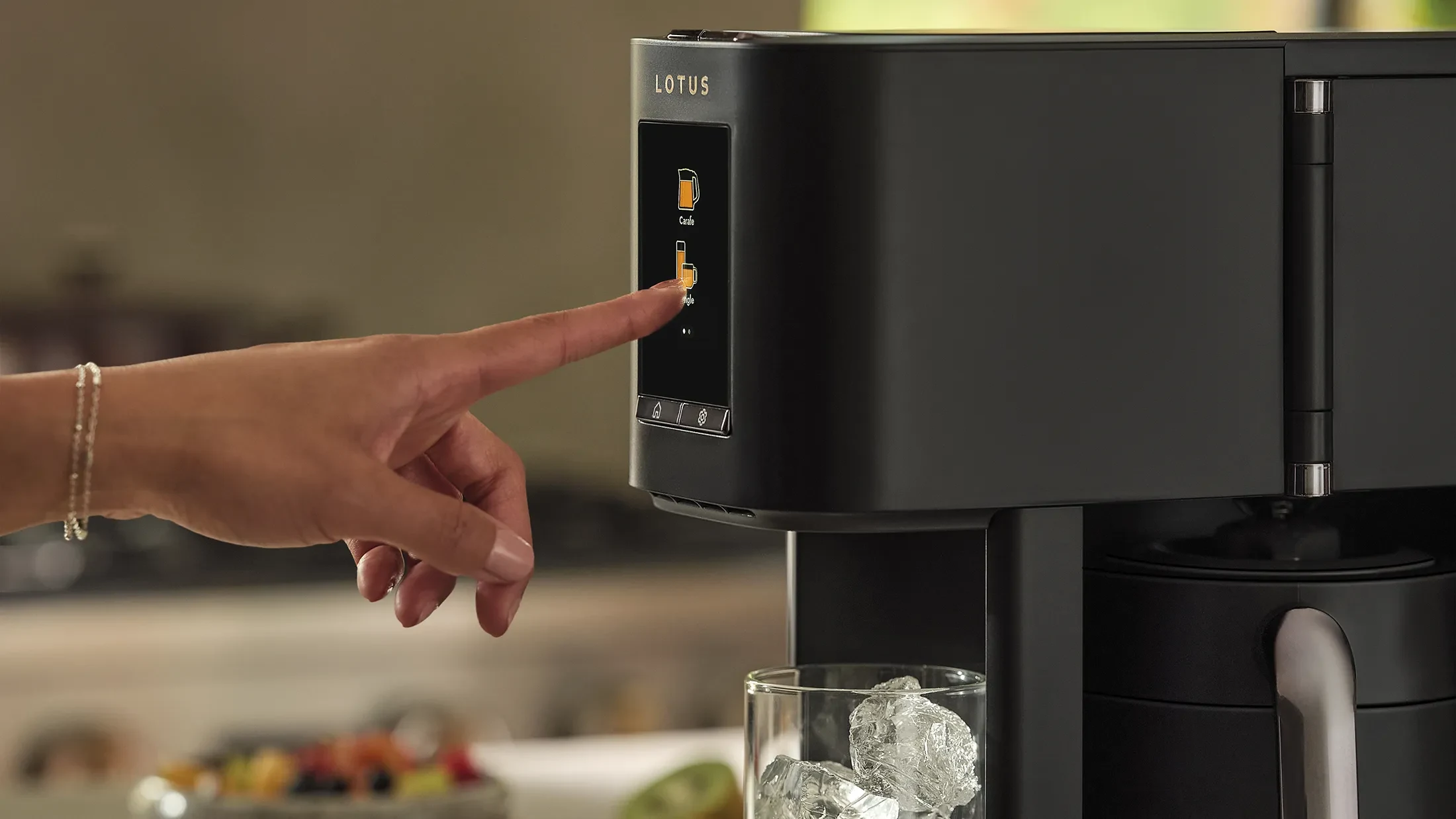 The Ritual coffee system in Obsidian with hand pressing the color touchscreen and ice visible in a glass underneath the dispenser