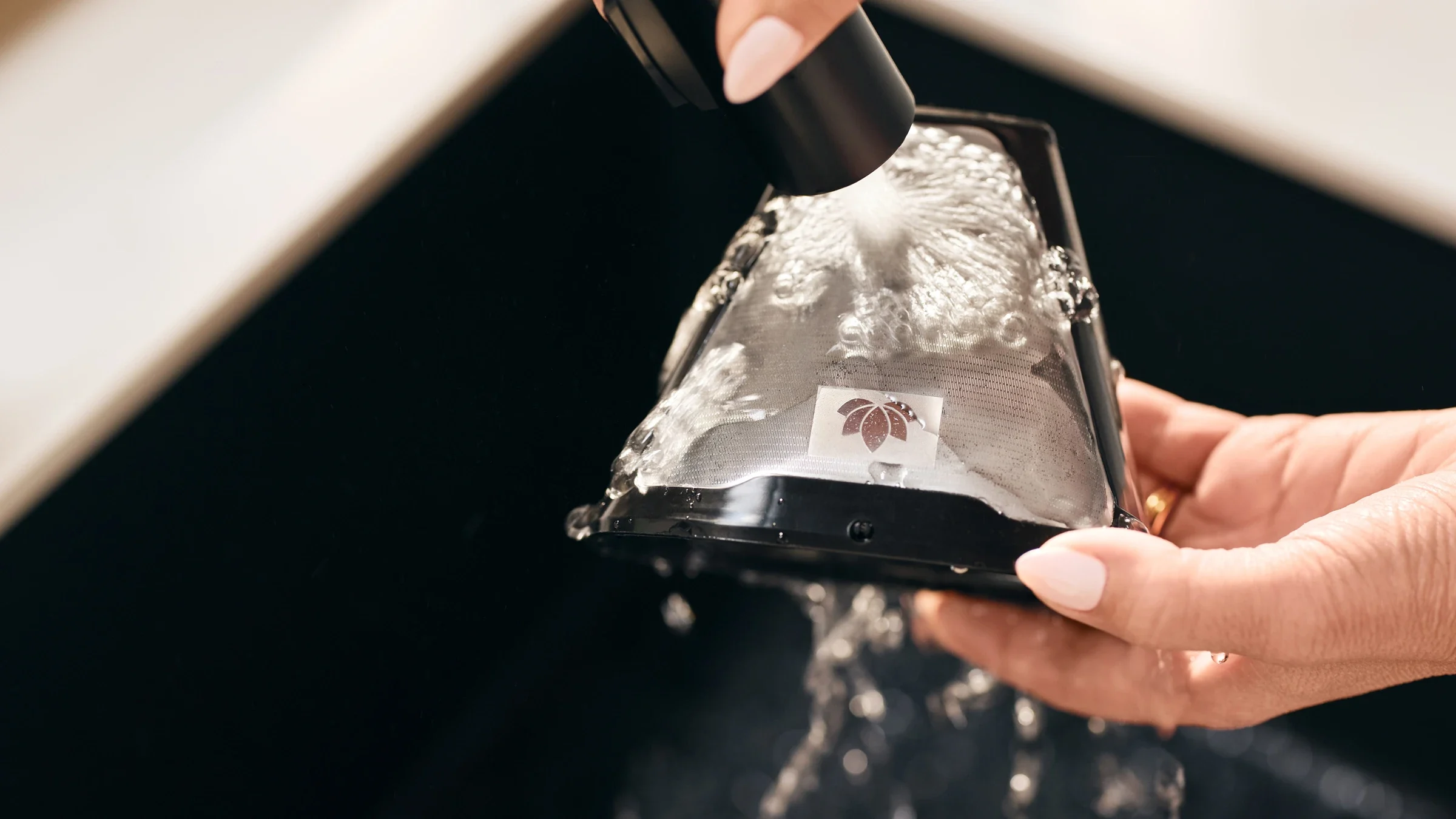 person cleaning the reusable coffee filter for the top drip™ coffee maker with grounds scale model ltsgr500