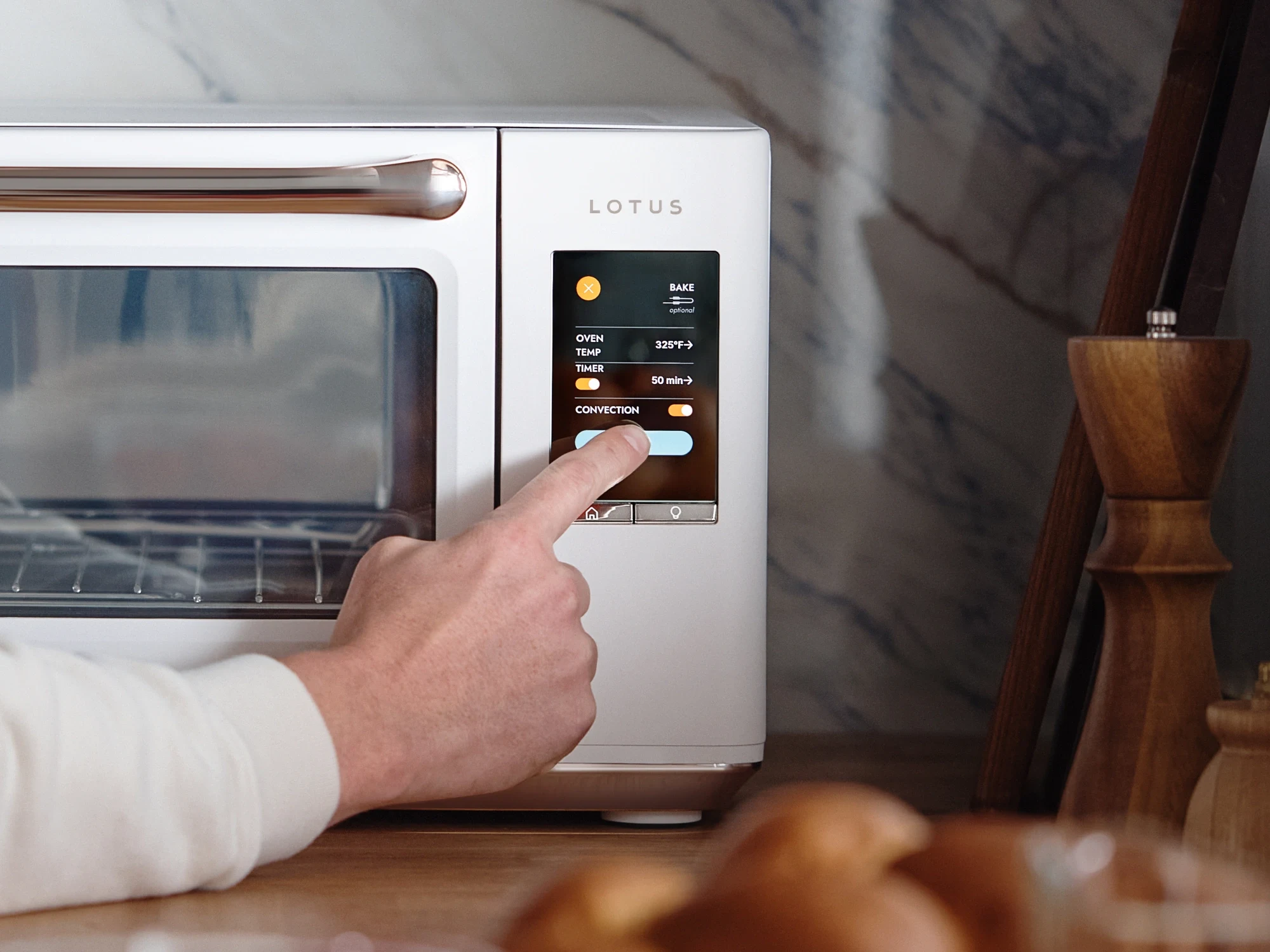 The Luminary oven in Alabaster with hand toggling Convection setting on the touchscreen