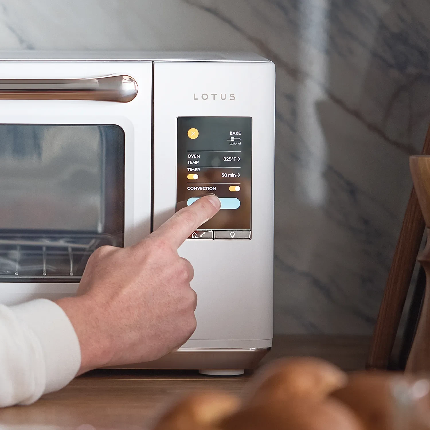 The Luminary oven in Alabaster with hand toggling Convection setting on the touchscreen