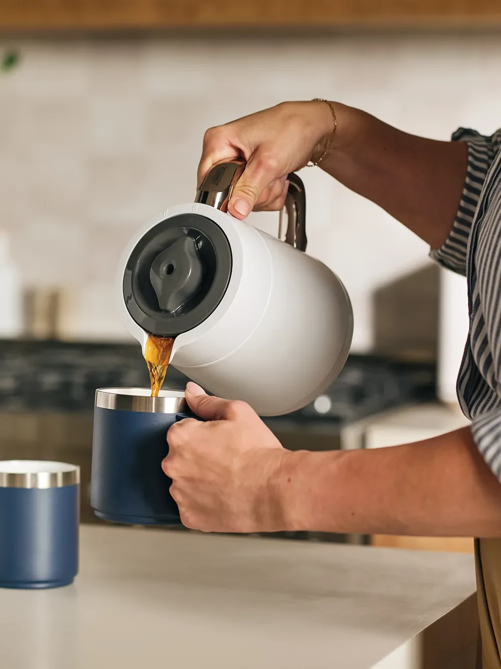 The Ritual coffee system in Alabaster with the insulated carafe pouring hot coffee into a mug