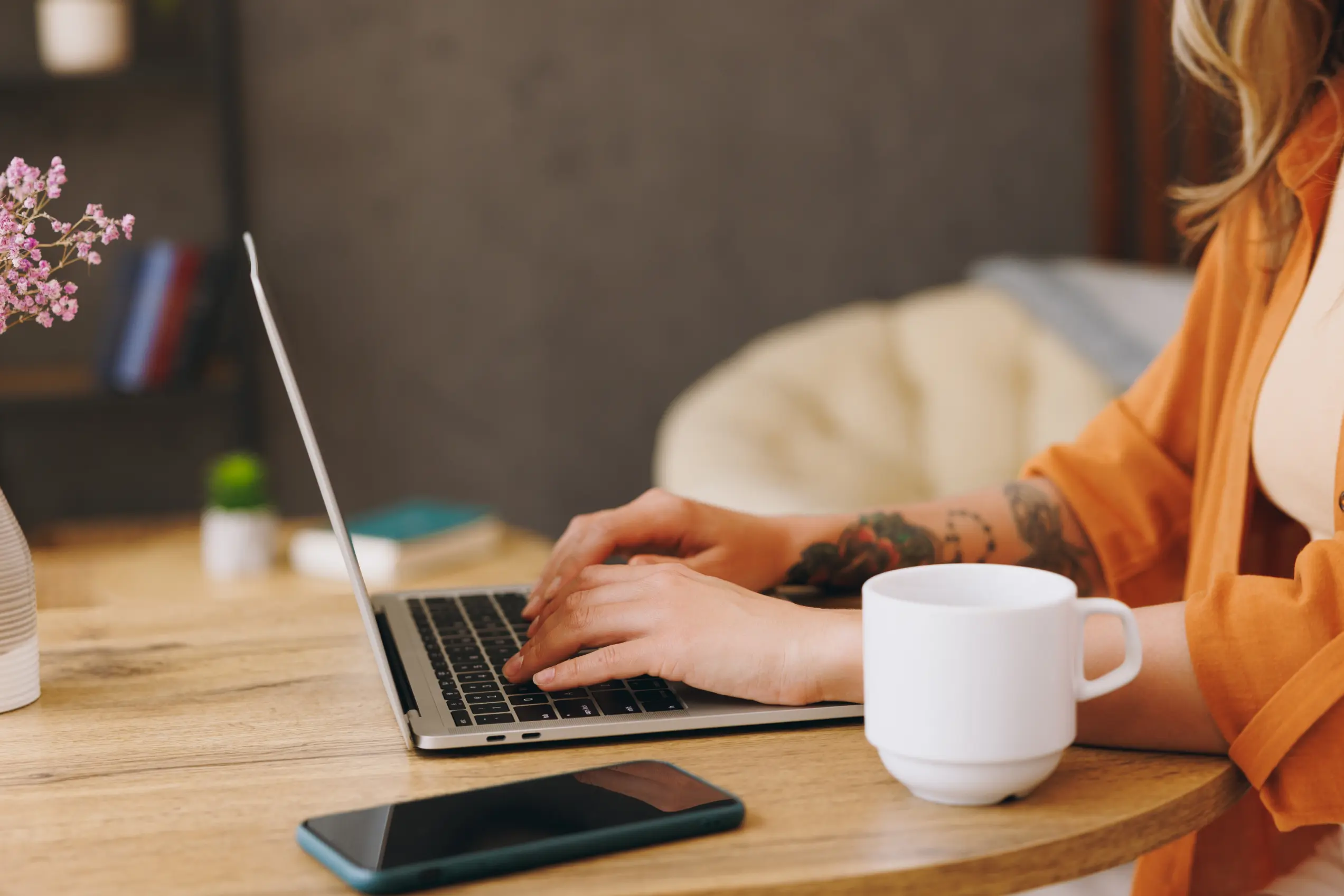 A close up of a student or borrower using a laptop and smartphone at a desk.