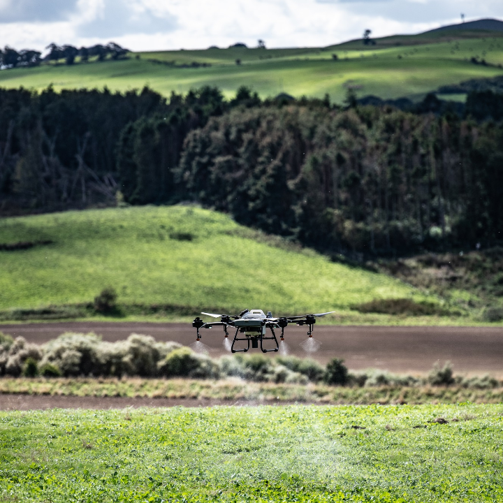 DJI Agras T25 flying over a field.