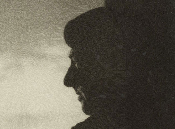 Silhouette of a man standing with a cigarette in his right hand