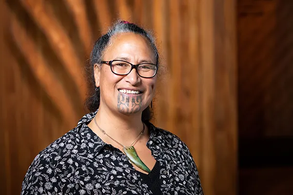 A woman with long hair wearing glasses and a tattoo on her chin