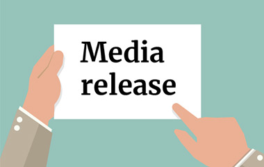 A colored illustration with two hands holding a white card with words Media release written on it, the card is on a teal background