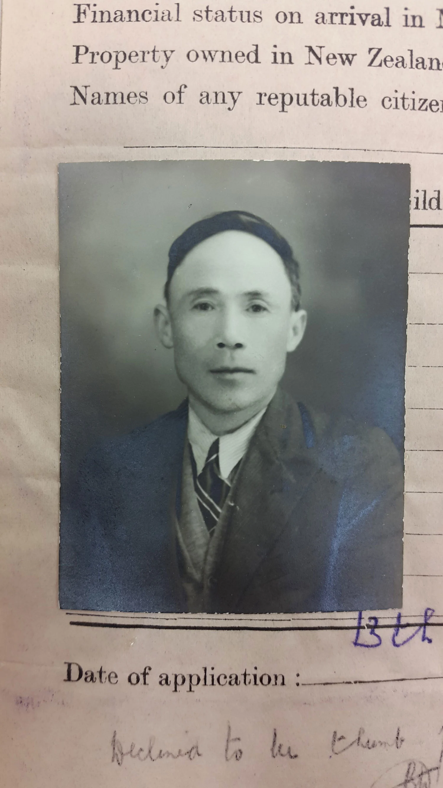 Black and white old photo of a man wearing suit and tie and having short hair, pasted on a yellowed old paper 