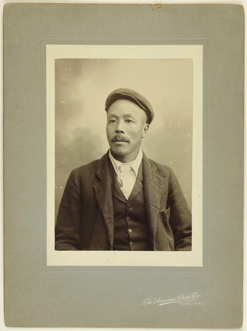 Sepia photo portrait of a Chinese man with moustache and flat cap